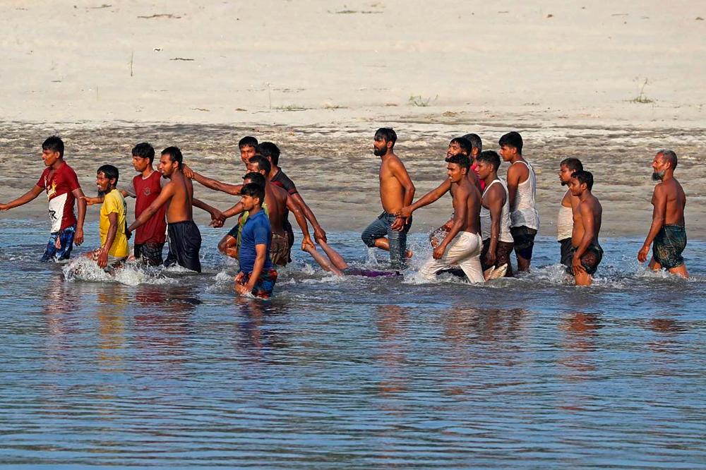 Orang ramai membawa mayat mangsa yang maut selepas bot karam di sungai Karotoa berhampiran bandar Boda pada 26 September 2022. fotoAFP