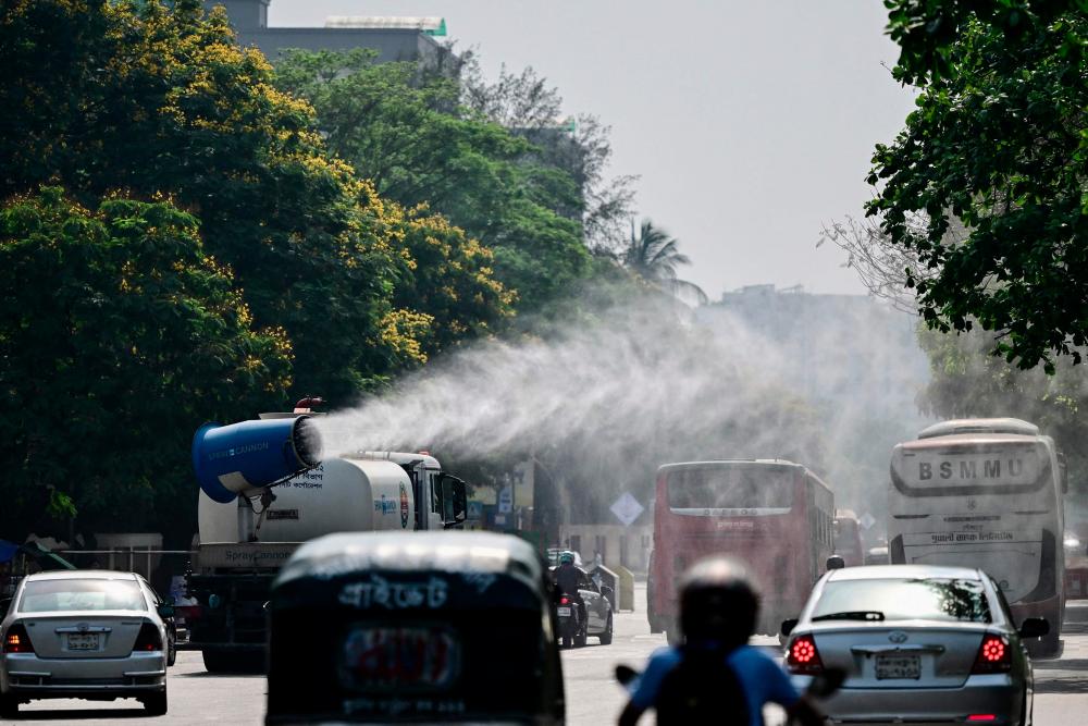 A vehicle of the Dhaka North City Corporation (DNCC) sprays water along a busy road to lower the temperature amidst a heatwave in Dhaka on April 27, 2024. - AFPPIX