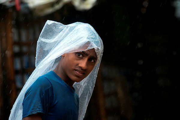 A Rohingya refugee youth covers his head with plastic as he walks during a monsoon rainfall at Kutupalong refugee camp in Ukhia on Setember 12, 2019. — AFP