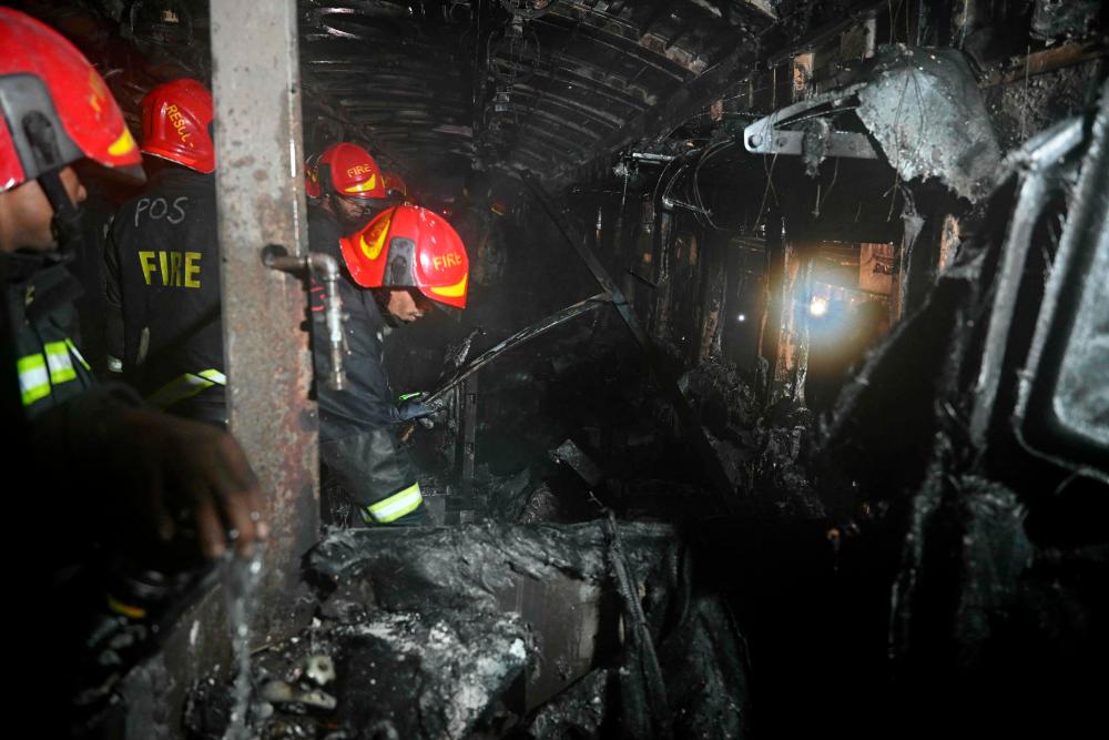 Bangladeshi rescue personnel search through a burnt out carriage of the Benapole Express in Dhaka on January 5, 2024/AFPPix