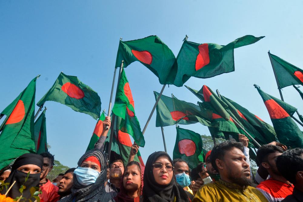 People wave national flags as they gather to pay their respects at the 1971 independence war's martyrs national memorial to celebrate the 50th Victory Day, which marks the end of a bitter nine-month war of independence from Pakistan, in Savar on December 16, 2021. AFPPIX