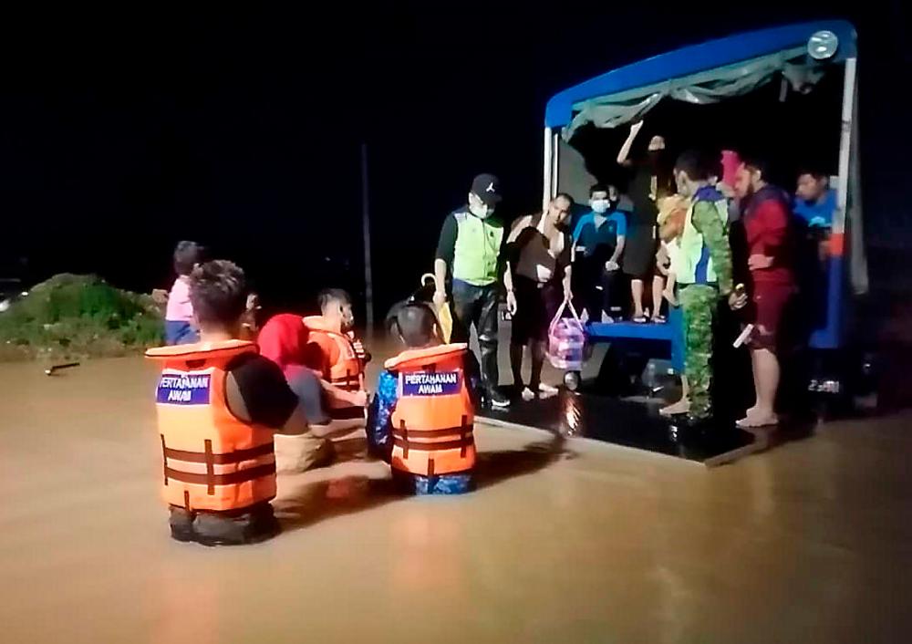 Kelihatan anggota Angkatan Pertahanan Awam Malaysia (APM) dengan kerjasama Polis dan Rela memindahkan mangsa-mangsa banjir di Kampung Kangkar Tebrau ke Pusat Pemindahan Sementara (PPS) di Sekolah Kebangsaan Bukit Mutiara malam ini. — Bernama