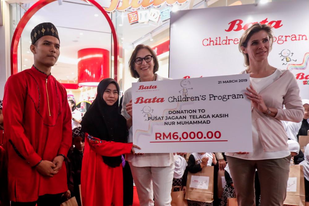 Bata Global board members Christine Schmidt (left) and Miriam Staub Bisang presenting the mock cheque to representatives from the orphanage. — Sunpix by Ashraf Shamsul