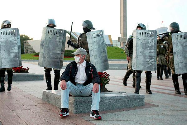 A man wearing a face mask sits in front of law enforcement officers during an opposition rally to protest against the presidential inauguration in Minsk on Sept 23, 2020. — AFP