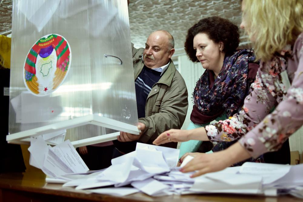Members of a local electoral commission empty a ballot box to count votes at a polling station after the Belarus' parliamentary election in the village of Kreva, some 10km northwest of Minsk, on Nov 17. — AFP