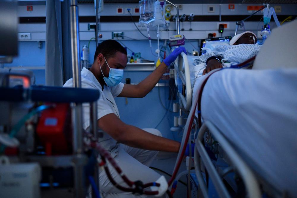 A medical staff's member assists a patient infected by Covid-19 at the intensive care unit of the Centre Hospitalier Regional de la Citadelle in Liege on December 21, 2021. AFPPIX