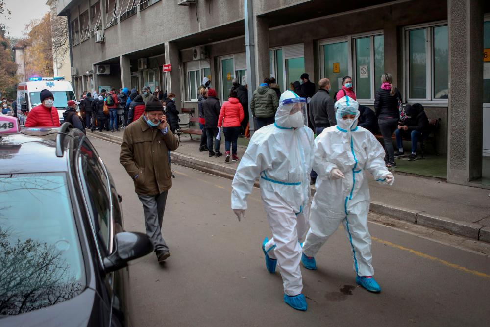 Medical workers wearing protective personal suit, walk outside the Clinic for Infectious and Tropical Diseases, in Belgrade, on November 24, 2020, as the number of Covid-19 cases rise again in Serbia. — AFP
