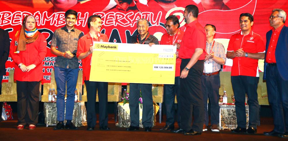 Azman (third left) presents a mock cheque for the member registration fees to Dr Mahathir (fourth left), witnessed by (from left) Rina, Syed Saddiq and others.