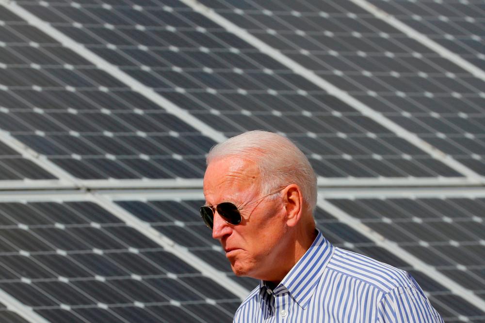 FILE PHOTO: Joe Biden walks past solar panels while touring the Plymouth Area Renewable Energy Initiative in Plymouth, New Hampshire, U.S., June 4, 2019. REUTERSpix