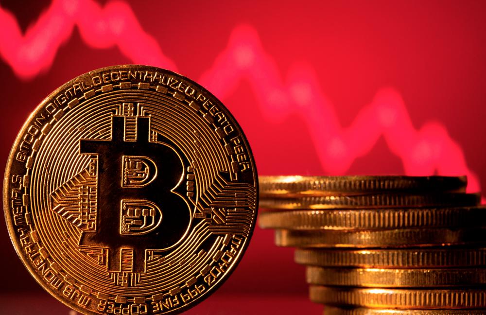 A representation of bitcoin is seen in front of a stock graph in this illustration. – Reuterspic
