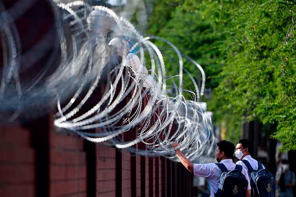 Students walk next to barbwire ahead of a mass rally to call for the ouster of Prime Minister Prayuth Chan-ocha’s government and reforms in the monarchy, at the Crown Property Bureau in Bangkok, Thailand, November 24, 2020. — Reuters