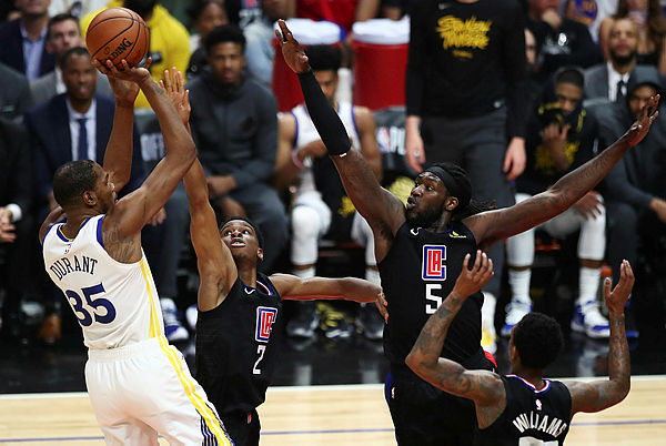 Kevin Durant of the Golden State Warriors shoots the ball against Shai Gilgeous-Alexander and Montrezl Harrell of the Los Angeles Clippers during the first half at Staples Center on April 18, 2019 in Los Angeles, California. — AFP