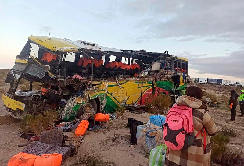 Handout picture released by Bolivian Police shows a woman walking close to the wreckage of a bus that collided with another one on a highway near Uyuni, Bolivia on March 1, 2025. Two passenger buses collided in the early hours of March 1, 2025, on a highway in southern Bolivia, leaving at least 37 dead, including two children, and some 30 people injured, police said. - AFP PHOTO / Bolivian Police / HANDOUT