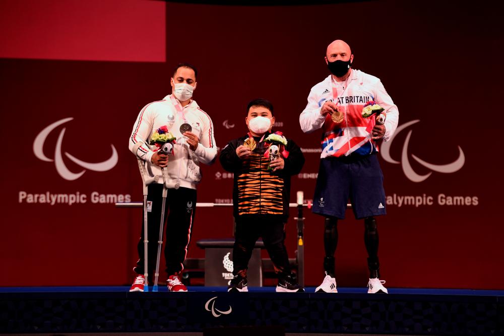 National paralympic powerlifting athlete Bonnie Bunyau Gustin (center) poses with athletes from Egypt and Great Britain, Attia Mahmoud (left) and Yule Micky after winning the country's first gold medal in the 72 kilogram (kg) category at the Tokyo 2020 Paralympic Games at the Tokyo International Forum today. BERNAMAPIX