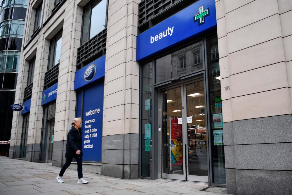 A woman entering a branch of Boots retailer and pharmacy in London today. – AFPPIX