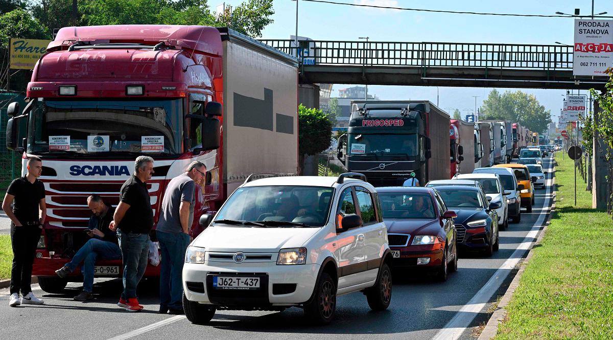 Vehicles drive past trucks partially blocking a highway exit leading towards the Bosnian capital of Sarajevo, on September 1, 2025. - ELVIS BARUKCIC / AFP