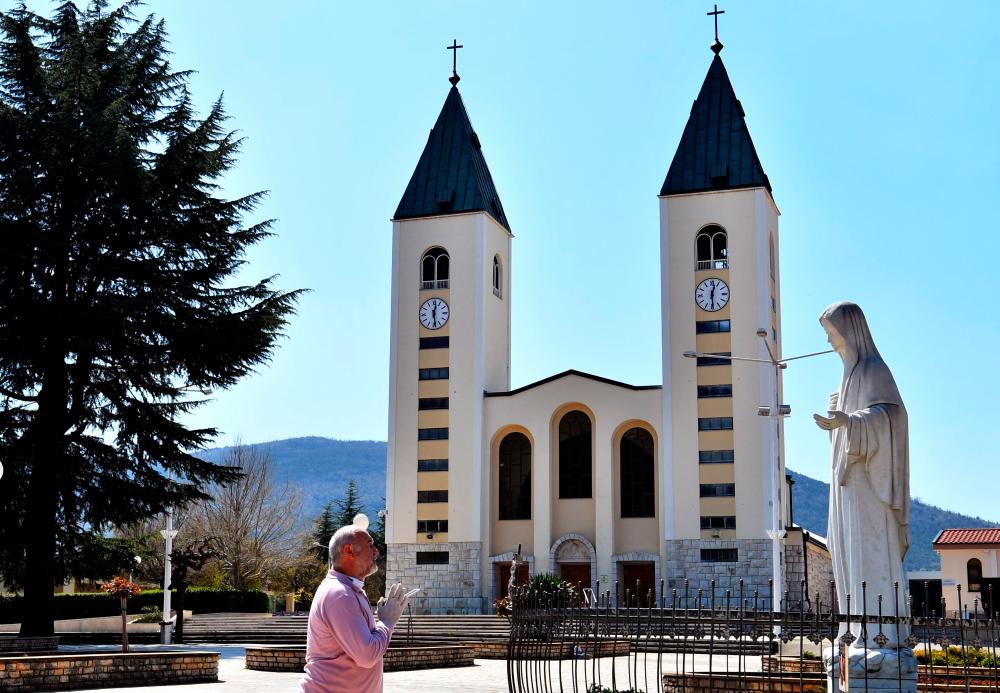Man prays in front of a Virgin Mary sculpture outside the St Jacob church, usually riddled with thousands of Catholic believers, at Marian pilgrimage site, in the southern Bosnian town of Medjugorje, on April 7, 2020 during a lockdown to stop the spread of COVID-19 (novel coronavirus). Ever since the Virgin Mary was said to appear before six teenagers on a hill in Bosnia four decades ago, pilgrims have flocked to the town of Medjugorje, eager to witness a miracle. — AFP