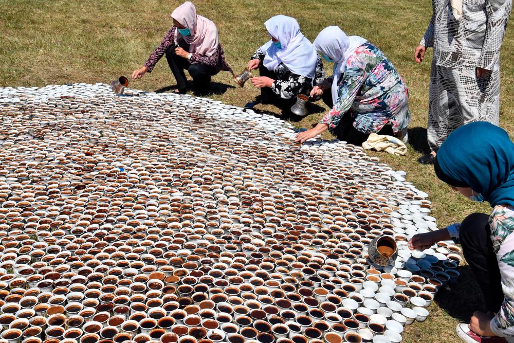 Bosnian Muslim women, survivors of the 1995 Srebrenica massacre help Bosnian artist Aida Sehovic near memorial cemetery in Potocari, near Srebrenica, on July 10, 2020, to fill up traditional coffee cups with coffee, while she sets up her installation Why Aren't You Here, consisted of 8000 coffee cups, that no one is going to drink. Relatives of the Bosnian Muslims killed in the worst atrocity on European soil since World War II are getting ready to mark 25 years since the Srebrenica massacre on July 11, but for many Serbs the episode remains a myth. Bosnian Serb forces killed more than 8,000 Muslim men and boys in a few days after capturing the ill-fated town on July 11, 1995. — AFP