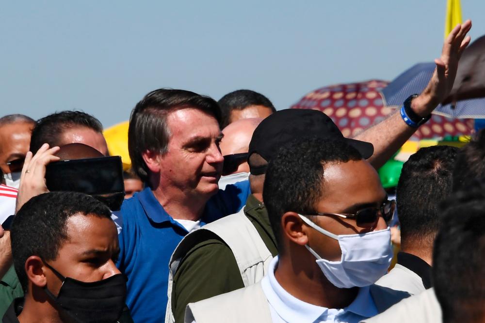 Brazilian President Jair Bolsonaro (C) greets supporters during a demonstration in Brasilia, on May 31, 2020 during the COVID-19 novel coronavirus pandemic. Bolsonaro, who fears the economic fallout from stay-at-home orders will be worse than the virus, has berated governors and mayors for imposing what he calls the tyranny of total quarantine. Even as his country surpassed France to have the world's fourth-highest death toll, Bolsonaro called for Brazil's football season to resume. - AFP