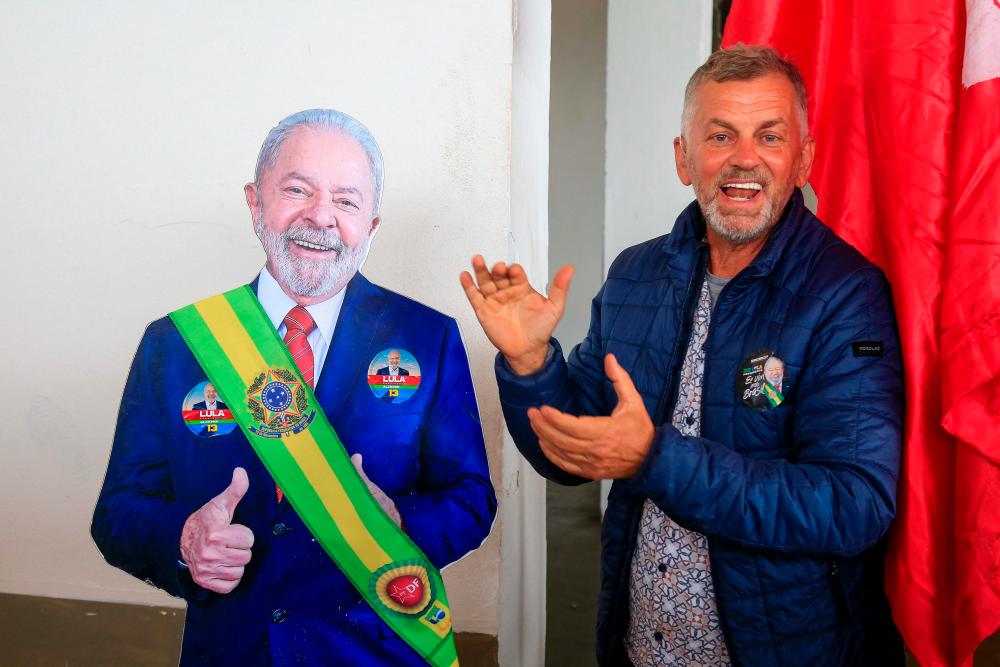 A supporter poses for a picture with a cardboard cutout of President-elect Luiz Inacio Lula da Silva while camping at the Brasilia Exhibition Pavilion to attend his inauguration ceremony in Brasilia on December 31, 2022. AFPPIX
