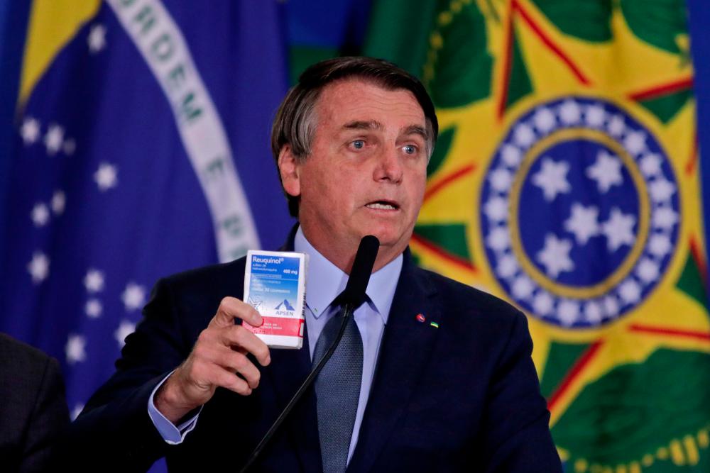 Brazilian President Jair Bolsonaro speaks holding a hydroxychloroquine box during the inauguration ceremony of Army General Eduardo Pazuello as Minister of Health at the Planalto Palace, in Brasilia, on Sept 16, 2020. — AFP