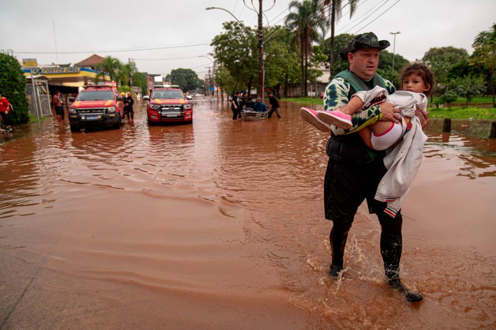 A child is evacuated from a flooded area in Porto Alegre, Rio Grande do Sul State, Brazil, on May 4, 2024. The death toll from floods and mudslides triggered by torrential storms in southern Brazil has climbed to 58 people, with the major city of Porto Alegre particularly hard-hit, the country's civil defense agency said Saturday.- AFPPIX