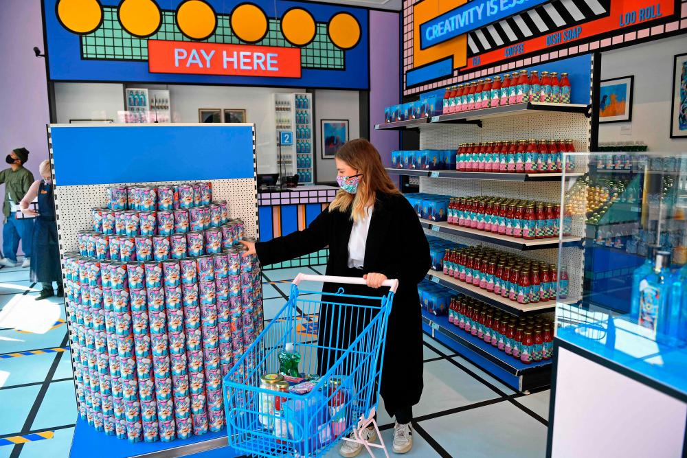 A gallery assistant fills a shopping trolley with products designed by emerging artists inside the newly created High Street shop in the Design Museum in west London on April 20, 2021 The 'supermarket' is stocking a range of products and packaging, designed by emerging artists and available for purchase. Money will go to the Design Museum’s new Emerging Designer Access Fund. –AFP