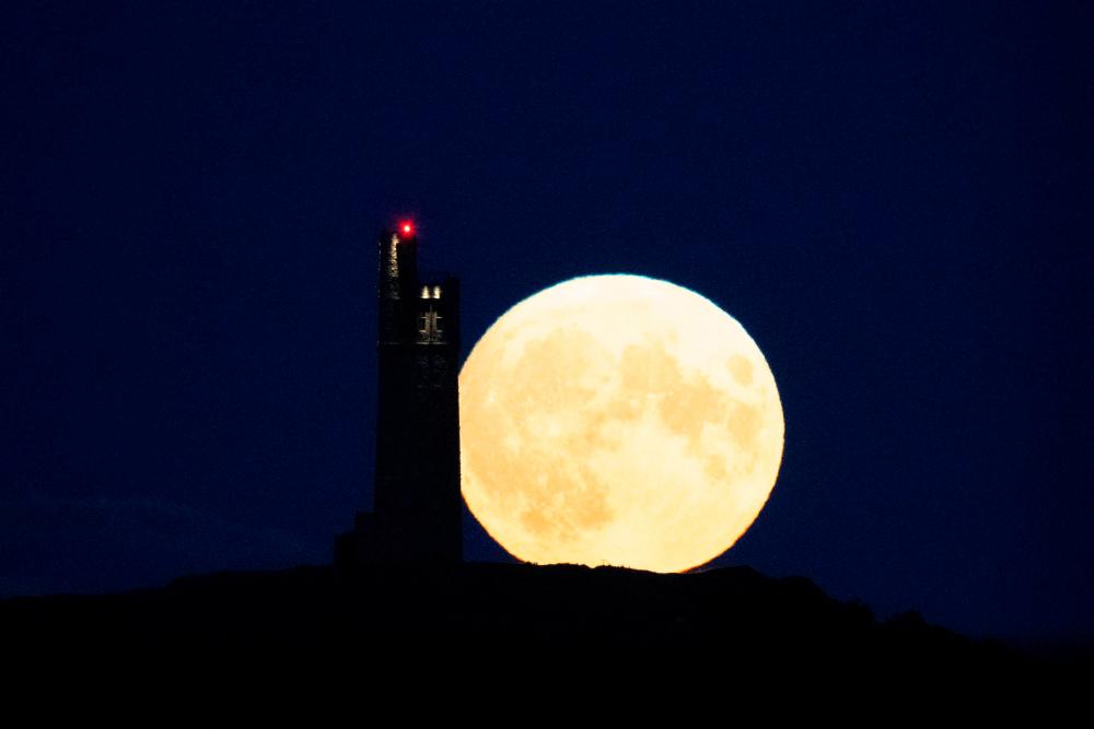 The full moon, called the Super Blue Moon, rises behind Victoria Tower on Castle Hill, above Huddersfield, on August 30, 2023/AFPPix