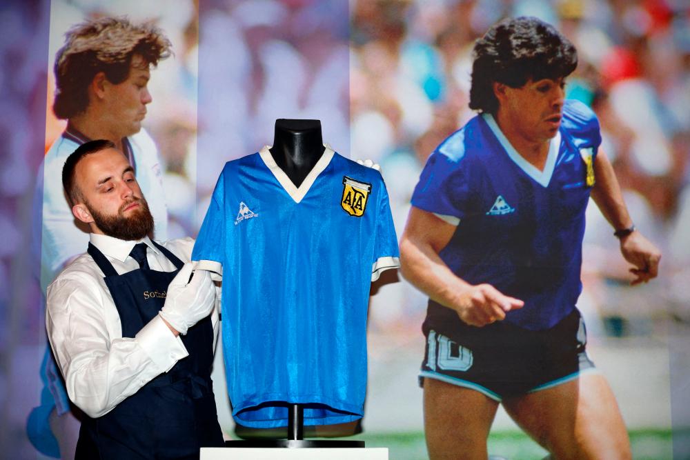 A Sotheby's technician adjusts a football shirt worn by Argentina's Diego Maradona during the 1986 World Cup quarter-final match against England, during a photocall at Sotheby's auction house in London/AFPPix