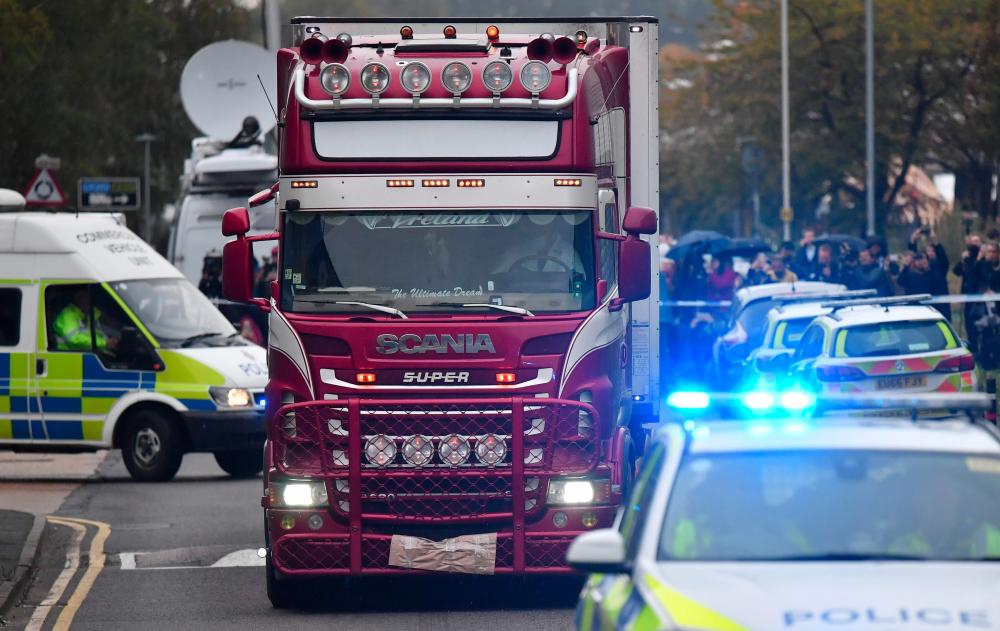File photo taken on Oct 23 shows police officers drive away a lorry (C) in which 39 dead bodies were discovered sparking a murder investigation at Waterglade Industrial Park in Grays, east of London. — AFP