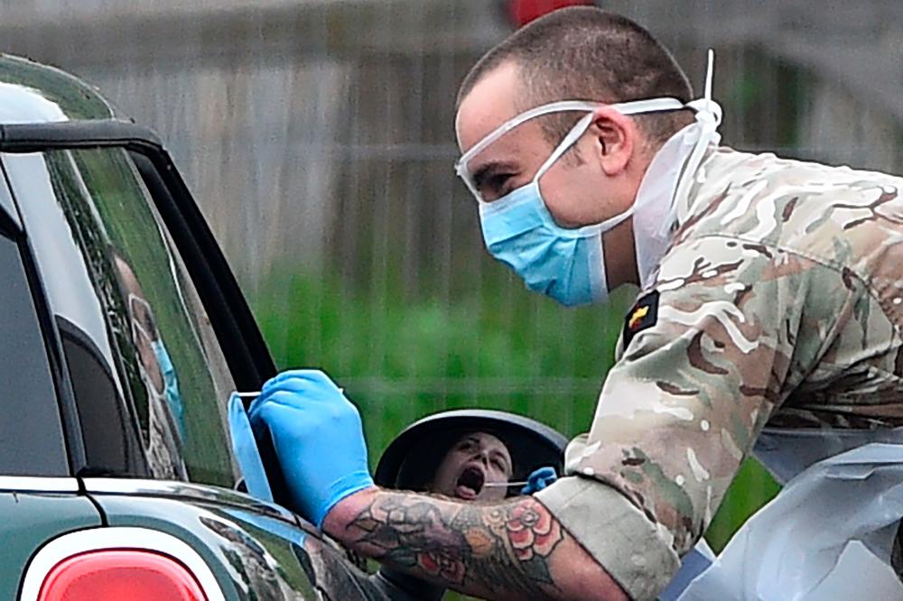 A member of the armed forces tests an NHS worker for the novel coronavirus COVID-19 at a testing facility at the Chessington World of Adventures Resort in Greater London on April 18, 2020. — AFP
