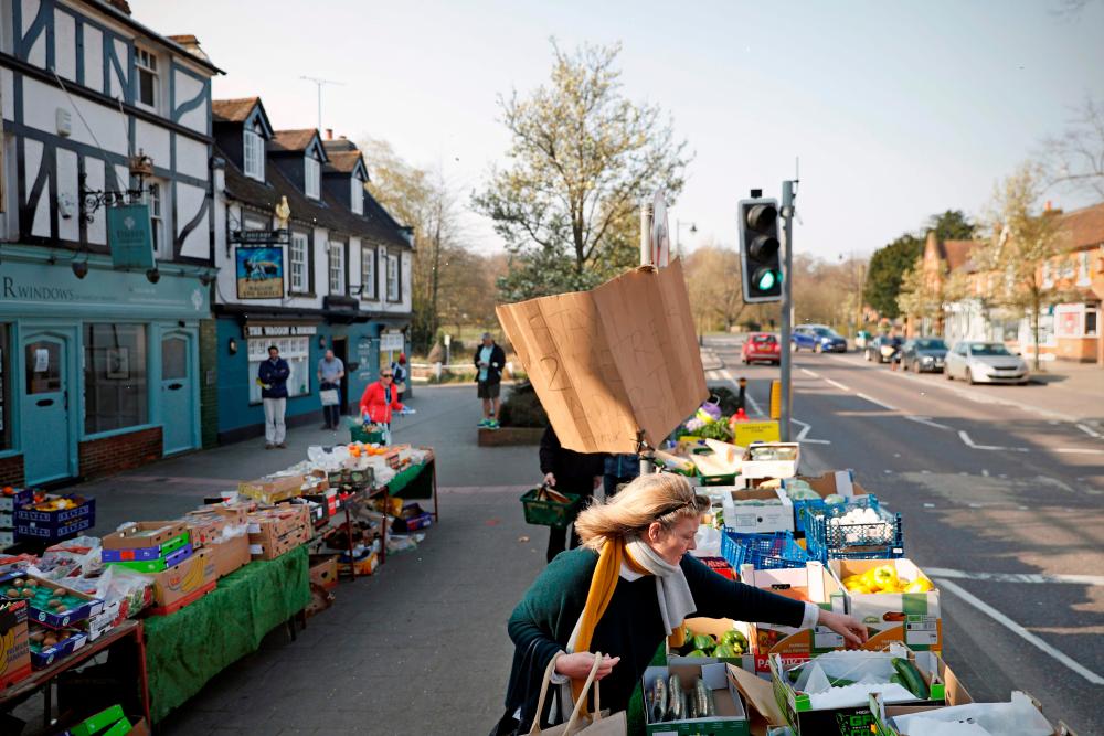 A woman shops at a fruit and vegetable market in Hartley Wintney, Hampshire on March 28, 2020. — AFP