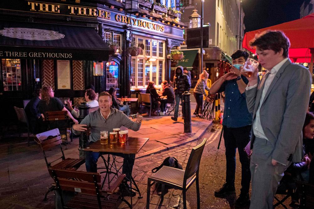 People drink at the outside tables of a pub in Soho, in central London on Sept 24, 2020, on the first day of the new earlier closing times for pubs and bars in England and Wales, introduced to combat the spread of the coronavirus. — AFP