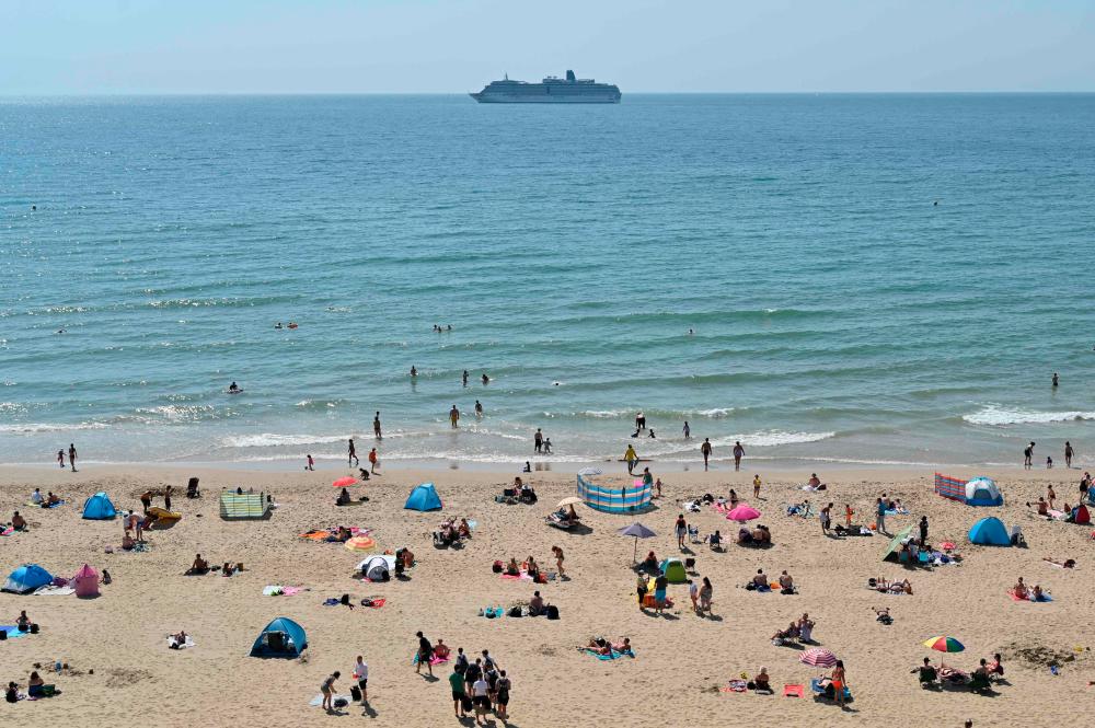 Beachgoers enjoy the sunshine as they sunbathe and play in the sea on Bournemouth beach in Bournemouth, southern England on July 31, 2020 as temperatures soar across the country. — AFP