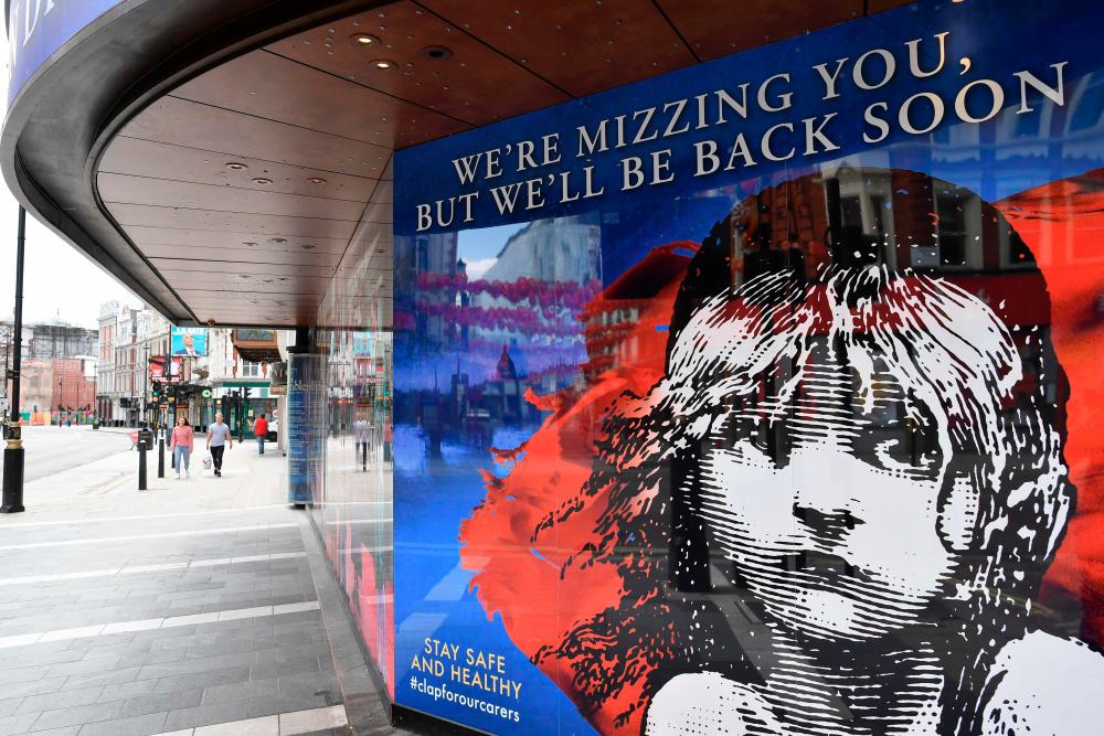 Pedestrians walk past the Sondheim Theatre, which would be showing Les Miserables, but is closed down as part of the COVID-19 pandemic enforced lockdown measures, in London on June 11, 2020. - AFP / JUSTIN TALLIS