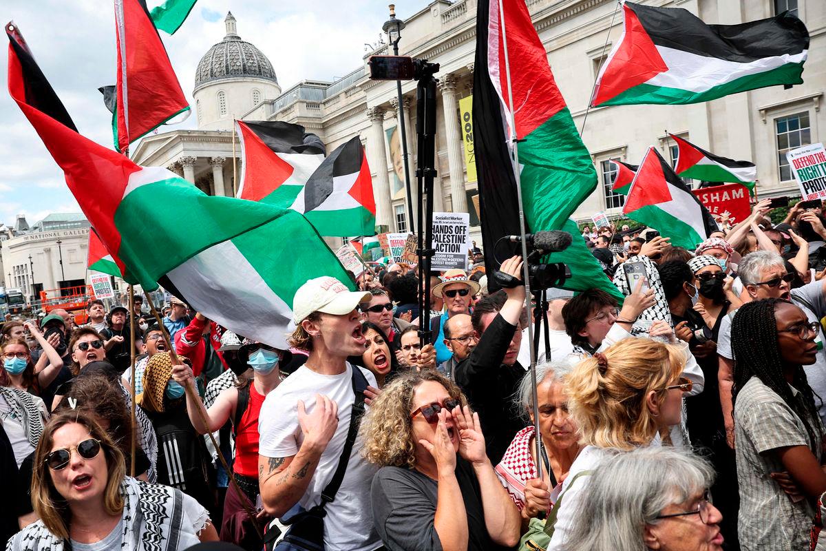 Protestors wave Palestinian flags in front of the National Gallery in Trafalgar Square as the rally for a protest in support of pro-Palestinian group Palestine Action, in central London, on June 23, 2025. (Photo by HENRY NICHOLLS / AFP)