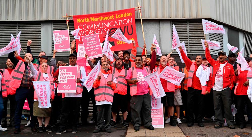 Royal Mail postal workers hold placards and chant slogans as they stand on a picket line outside a delivery office, in north London/AFPPix