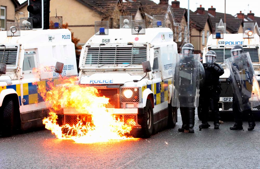 Flames lick up the front of a police vehicle as police officers are attacked by nationalist youths in the Springfield Road area of Belfast on April 8, 2021 following days of loyalist violence. Northern Ireland police faced a barrage of petrol bombs and rocks on on April 8. –AFP