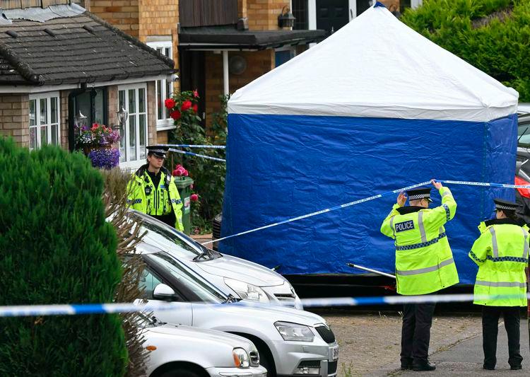 Police officers stand guard by a forensic team tent at Ashley Close in Bushey in the borough of Hertfordshire, north of London yesterday after a triple “crossbow attack” murder - AFPpix