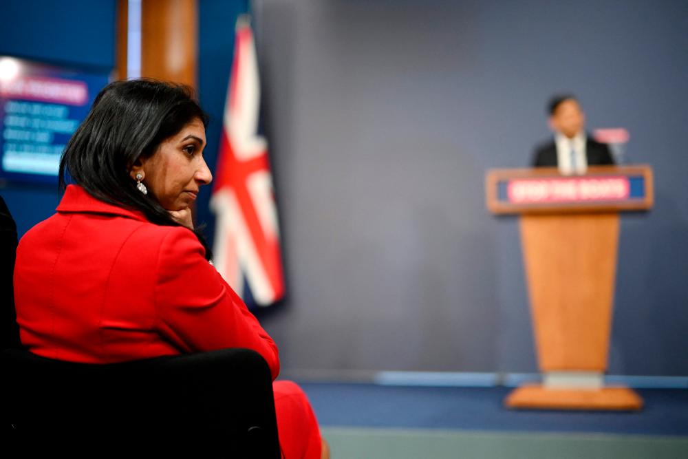 Britain's Home Secretary Suella Braverman listens as Britain's Prime Minister Rishi Sunak speaks during a press conference in the Downing Street Briefing Room in central London on March 7, 2023, following the announcement of the on the Illegal Migration Bill. AFPPIX