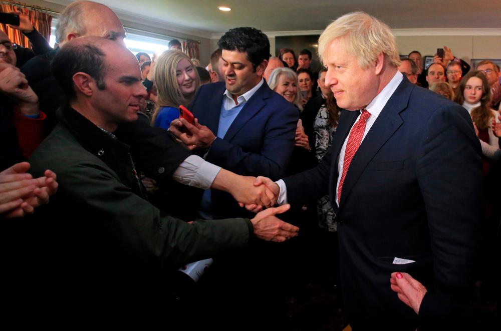 Britain's Prime Minister Boris Johnson shakes hands with supporters during a visit to see newly elected Conservative party MP for Sedgefield, Paul Howell at Sedgefield Cricket Club in County Durham, north east England on December 14, 2019, following his Conservative party's general election victory. - Reuters