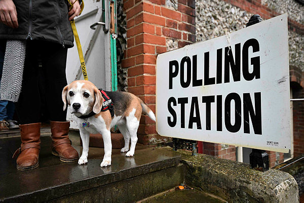 A voter leaves with their dog Lilly, after casting their vote at a polling station in Church in Brighton as Britain holds a general election on Dec 12, 2019 — AFP