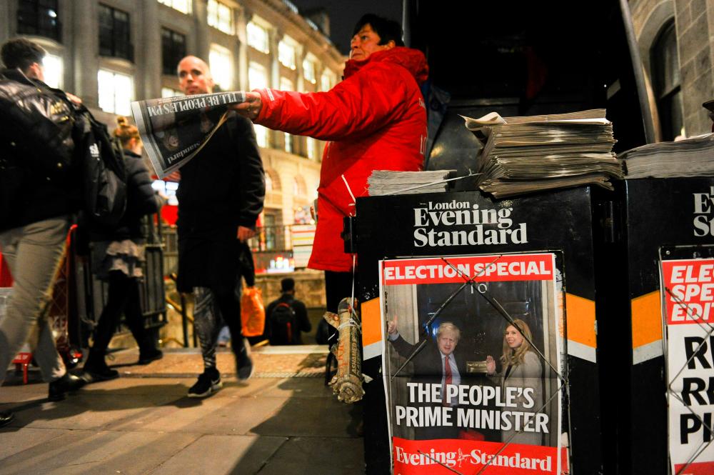 A vendor hands out copies of the London Evening Standard newspaper in London on December 14, 2019, with the front page reporting on the election victory of Prime Minister Boris Johnson's Conservative Party in the general election. - AFP