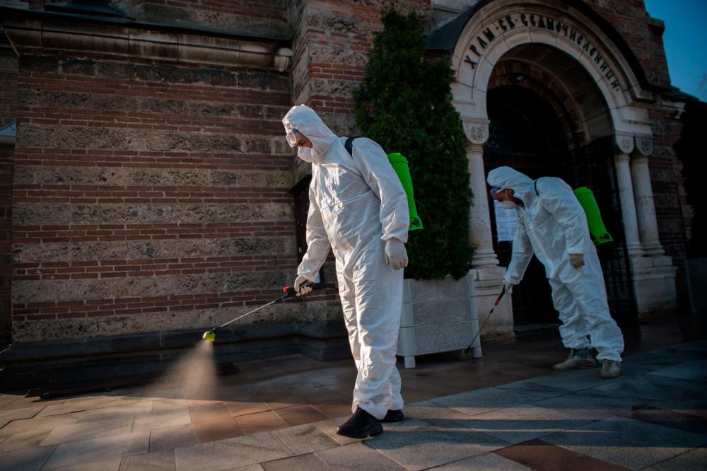 Members of the Sofia's Municipality disinfect the area in front of the Seven Saints Church in Sofia, to prevent the spread of the COVID-19, the novel coronavirus on April 11, 2020. — AFP