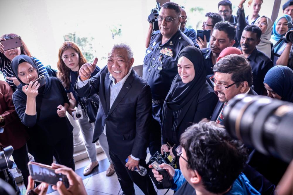 Kinabatangan MP and former Federal Land Consolidation and Rehabilitation Authority (Felcra) Berhad chairman, Datuk Seri Bung Moktar Radin gives the thumbs up to the media upon arrival at the Kuala Lumpur sessions court, with his wife Datin Seri Zizie Izette A. Samad, on May 3, 2019. — Sunpix by Adib Rawi Yahya