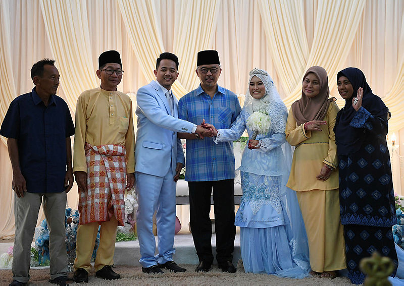 Sultan Abdullah flanked by the happy couple during the wedding reception. — Bernama