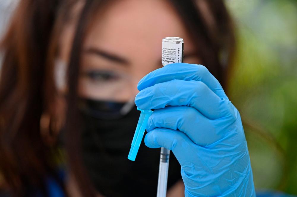 A healthcare worker fills a syringe with Pfizer Covid-19 vaccine at a community vaccination event in a predominantly Latino neighborhood in Los Angeles, California, Aug 11, 2021. — AFP
