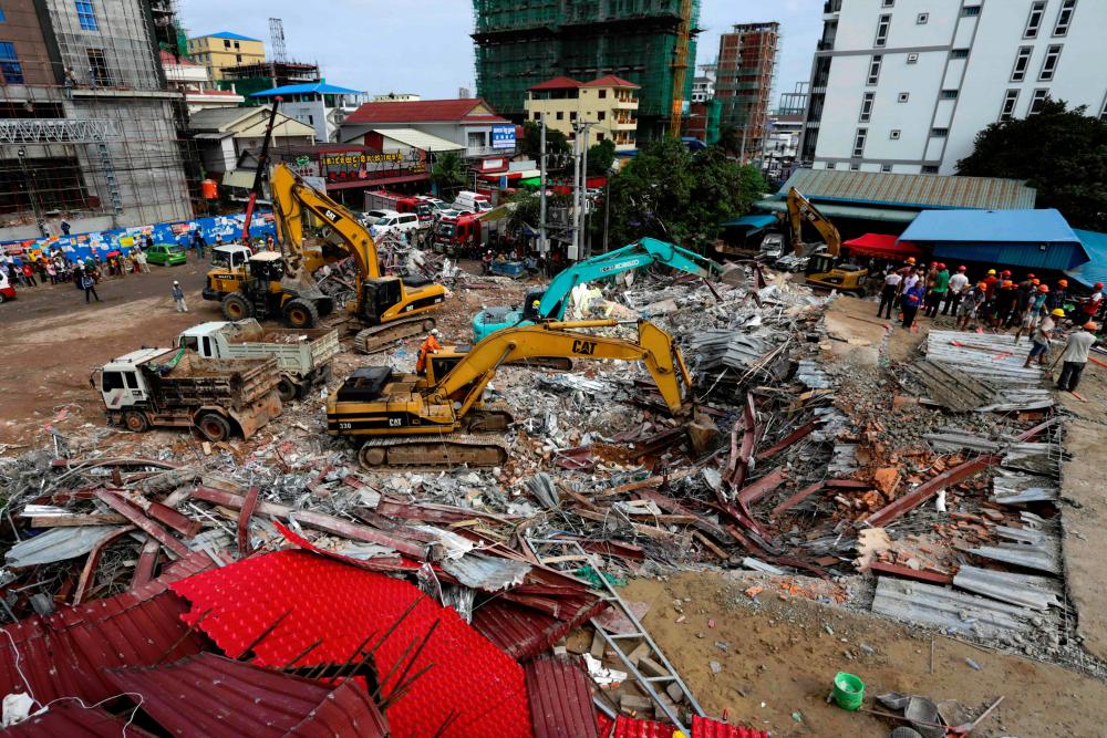 Rescue workers use earthmovers to clear debris as they search for victims a day after an under-construction building collapsed in Sihanoukville on June 23, 2019. — AFP