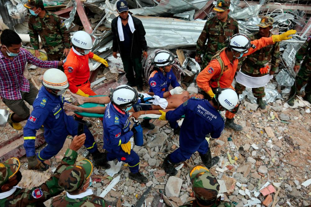 A survivor is carried out of the rubble from a collapsed building in Sihanoukville on June 24, 2019. Two men were pulled alive from the rubble of a collapsed Cambodian building on June 24, according to an AFP reporter at the scene, more than two days after the construction site accident that left at least 25 dead. — AFP