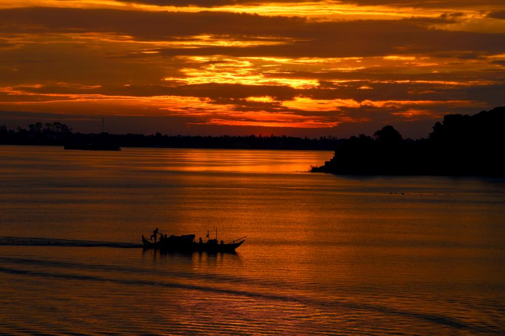 A fishing boat travels along the Mekong River at sunrise on the outskirts of Phnom Penh on June 1, 2020. - AFP